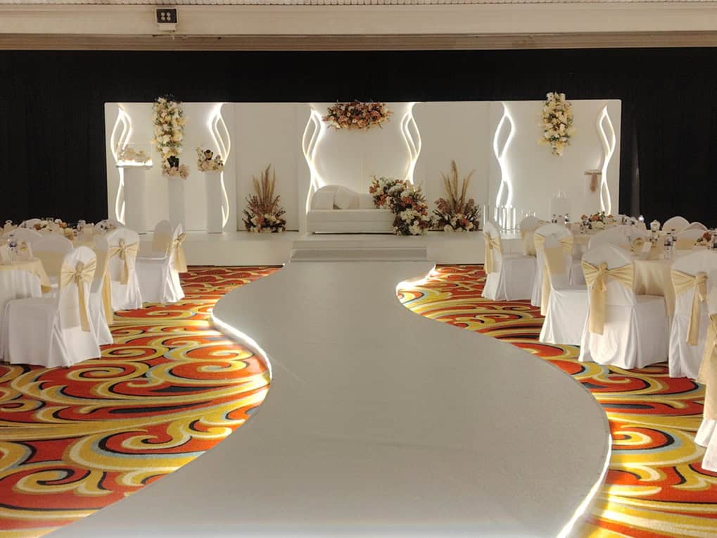 Luxury ballroom event setup with elegant stage, floral décor, and ambient lighting in UAE. تجهيز حفلة فاخرة في قاعة راقية مع كوشة أنيقة وتنسيقات زهور وإضاءة مميزة في الإمارات